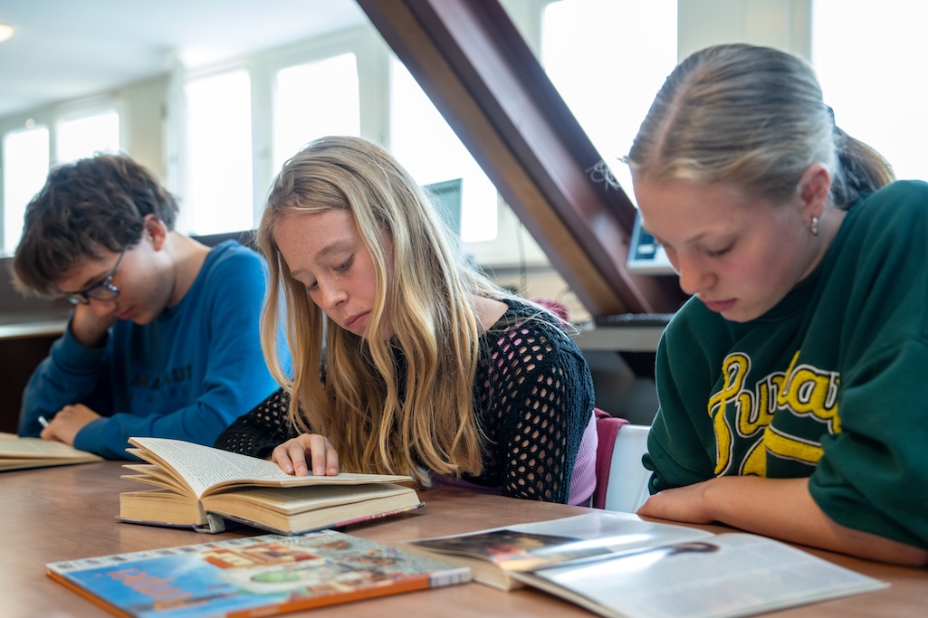 Leerlingen lezen aan tafel in mediatheek