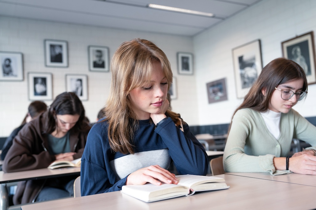 Leerling leest boek op tafel.