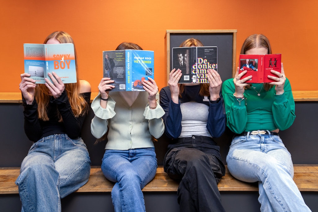 Leerlingen met boeken voor gezicht.