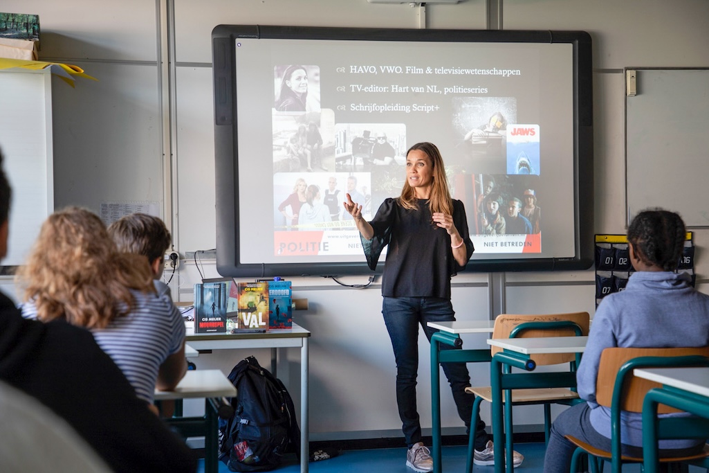 Docent voor de klas, op de achtergrond een Digibord