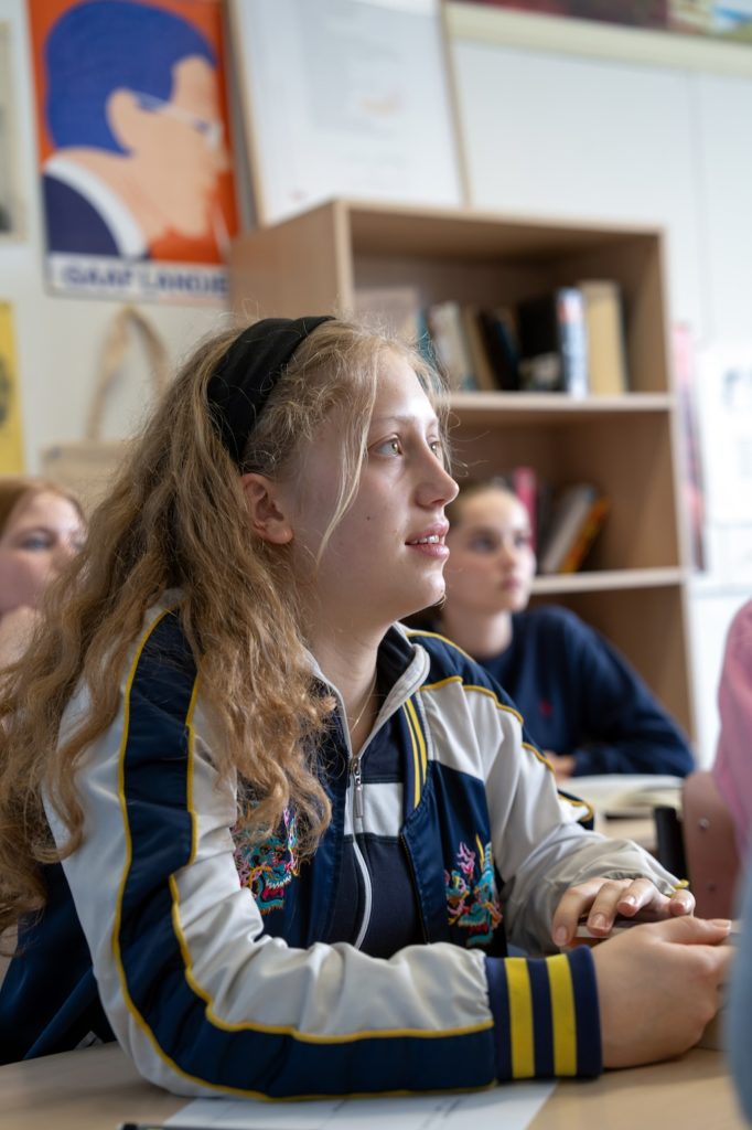 Leerling met blond haar en een haarband let op in de klas.