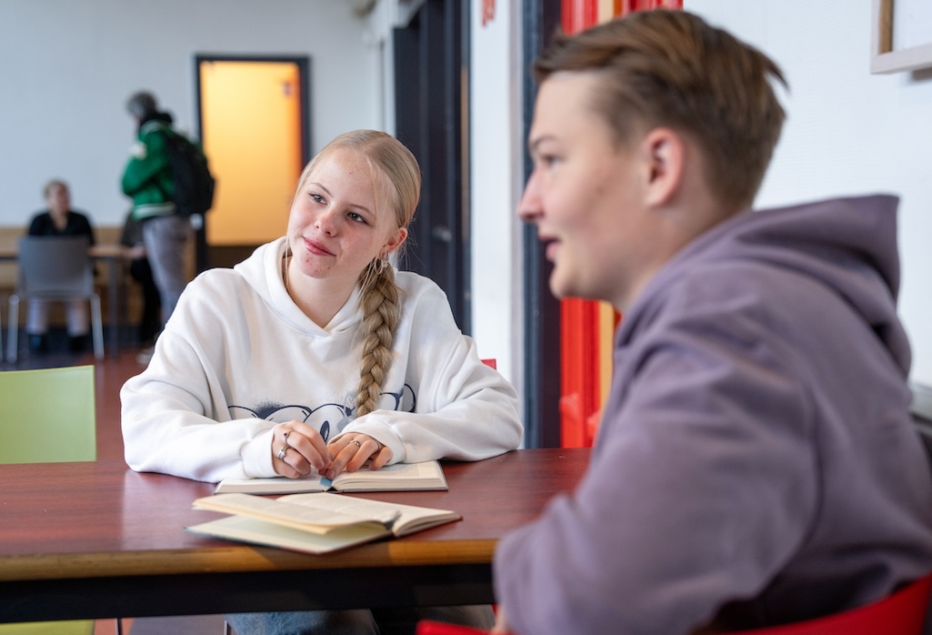 Twee leerlingen in de klas luisteren naar een derde persoon.